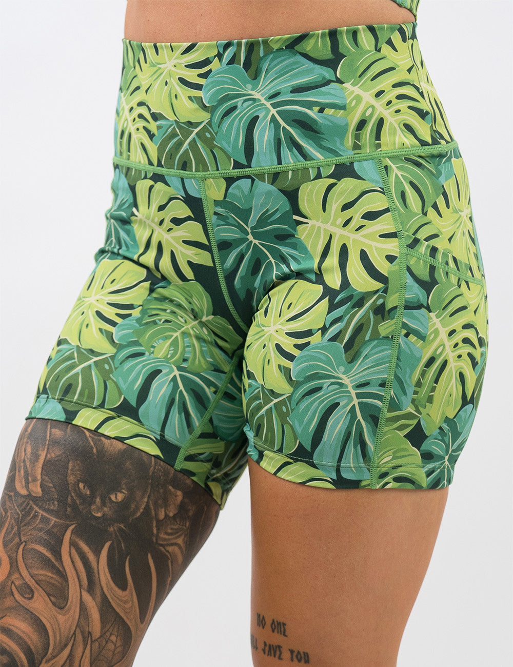 front of the 5 inch green tropical leaves shorts against a white background