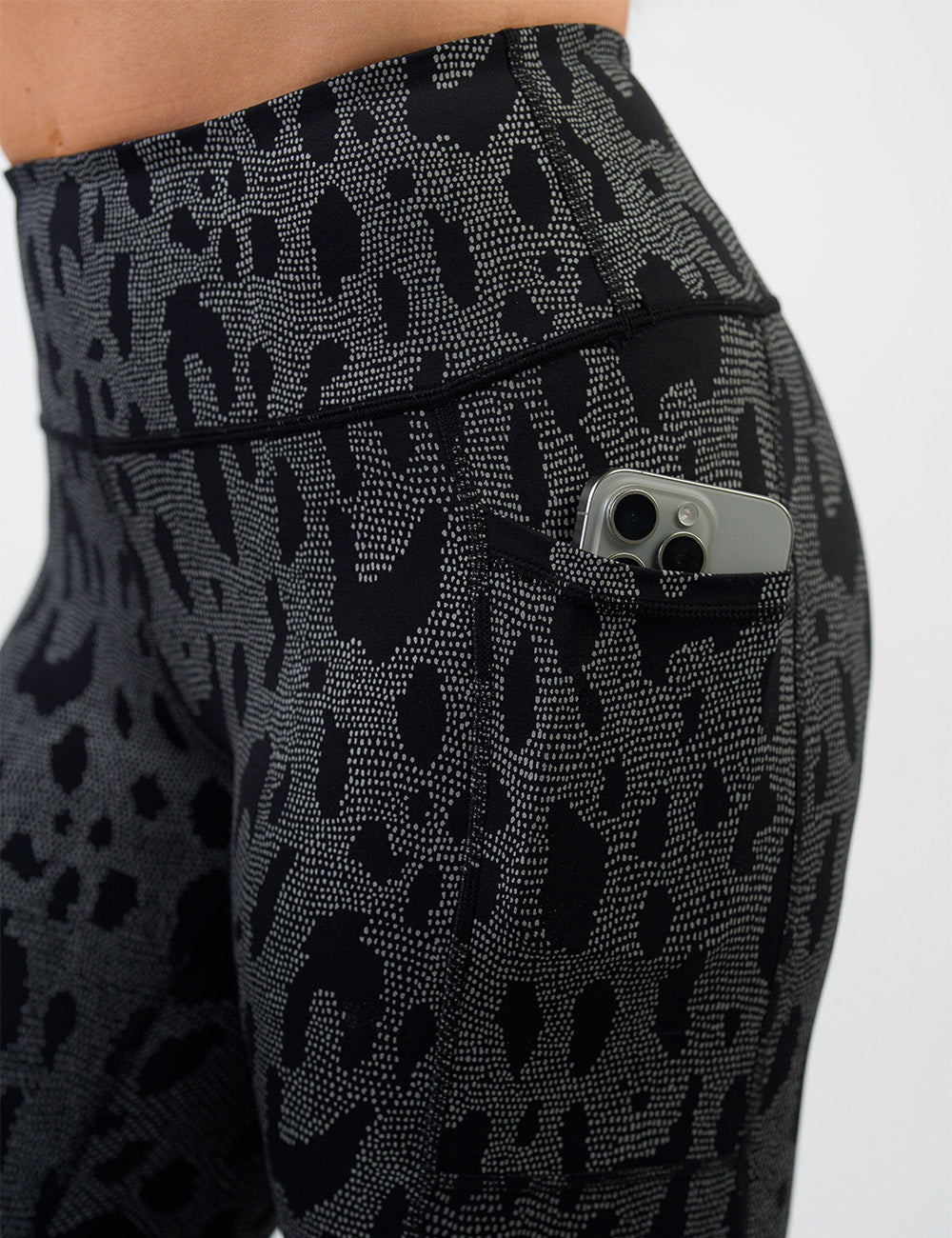 close up of the dark spots surrounded by a reflective background leggings with a phone in its pocket