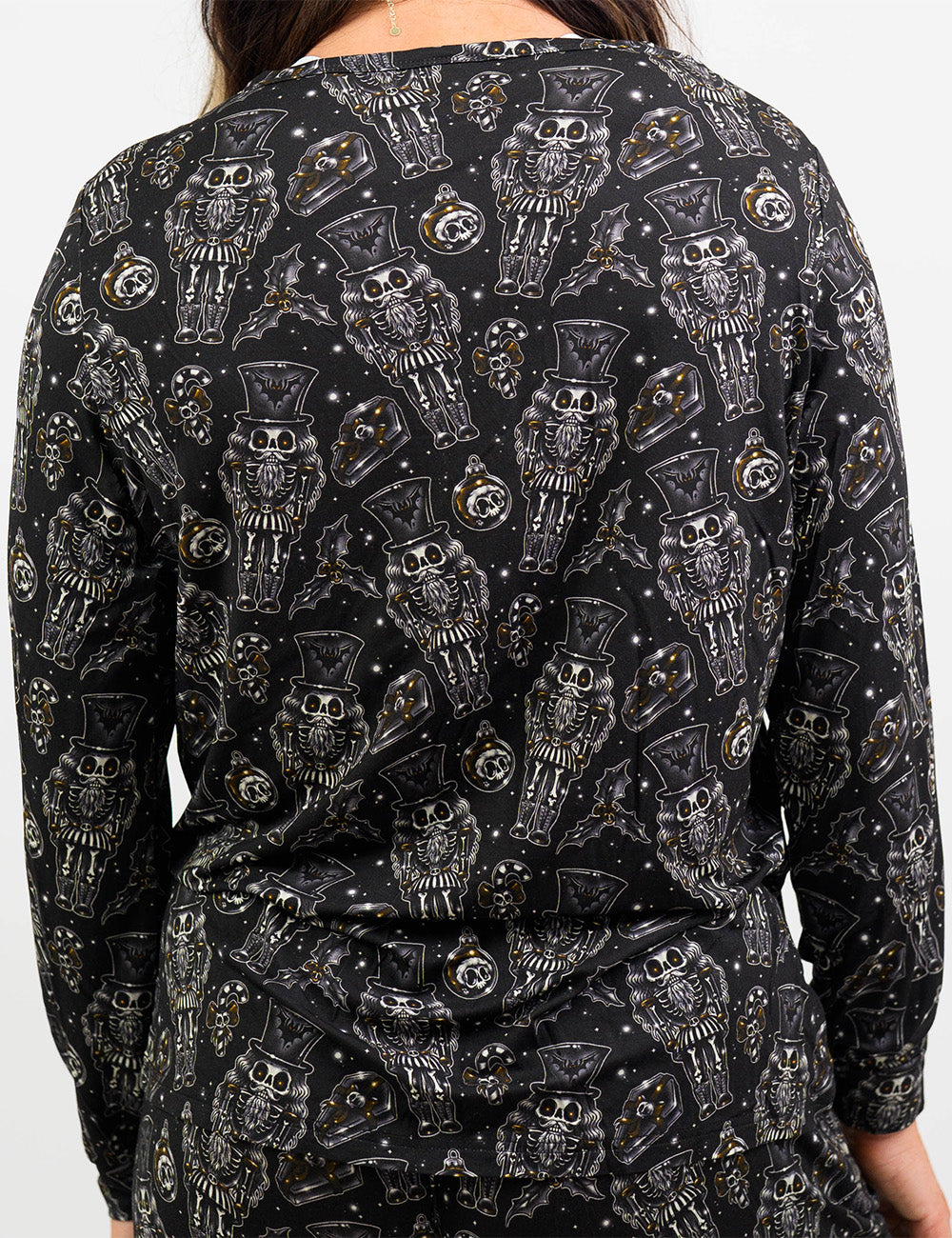 back of the black nutcrackers, mistle toe, and Christmas ornaments pajama top against a white background