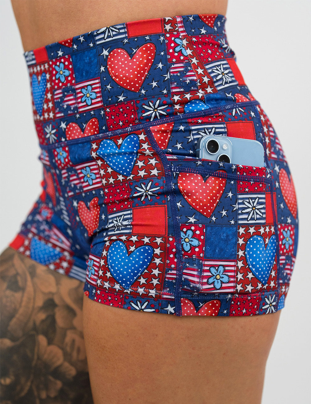 close up of the 2.5 inch patchwork american flag with red and blue hearts pattern shorts with a phone in it's pocket