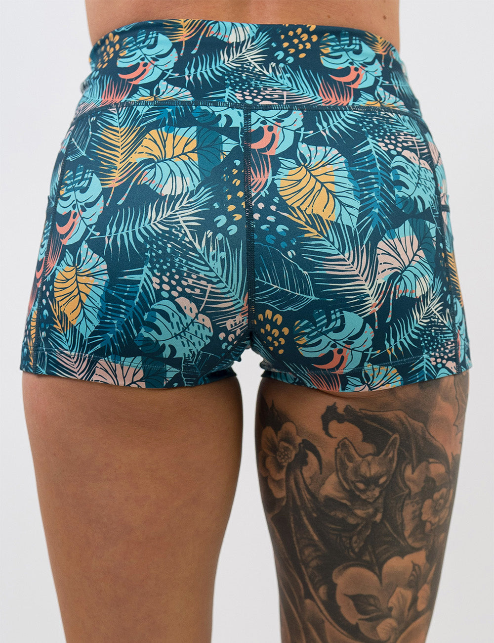 back of the 2.5 inch blue, pink, yellow, and red tropical leaves shorts against a white background