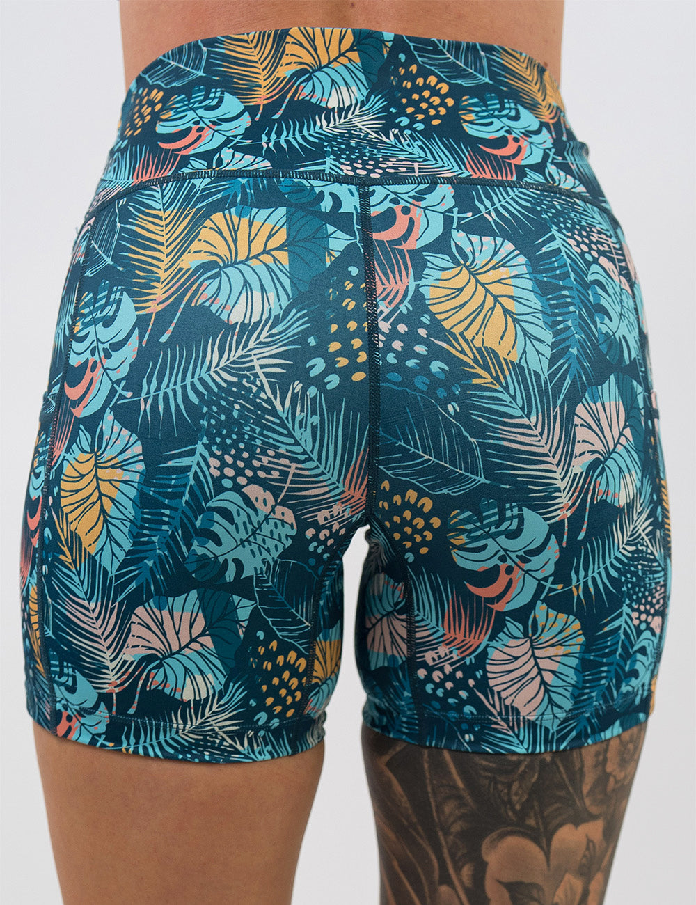 back of the 5 inch blue, pink, yellow, and red tropical leaves shorts against a white background