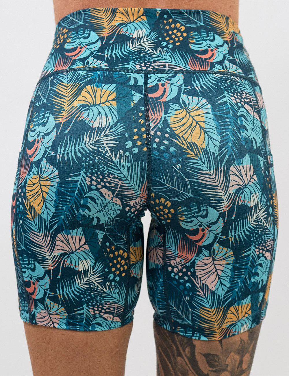 back of the 7 inch blue, pink, yellow, and red tropical leaves shorts against a white background