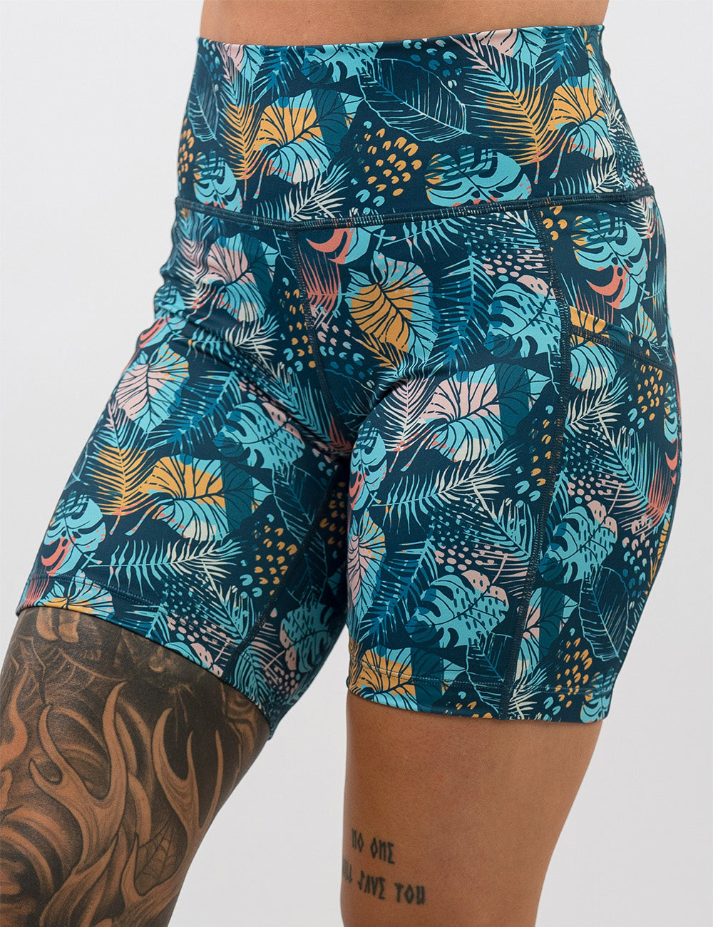 front of the 7 inch blue, pink, yellow, and red tropical leaves shorts against a white background
