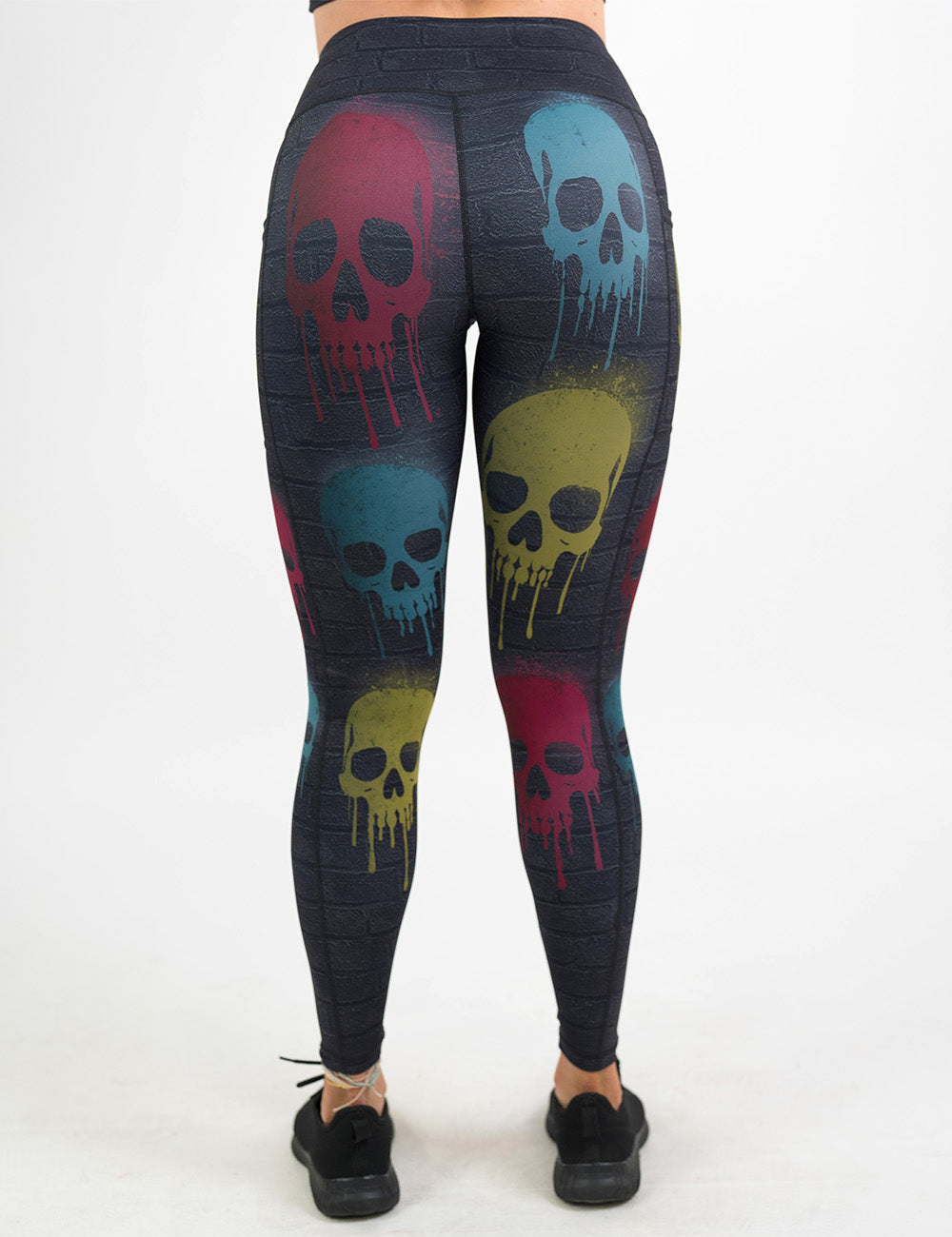 back of the black brick full length leggings with spray painted red, yellow, and blue skulls all over against a white background