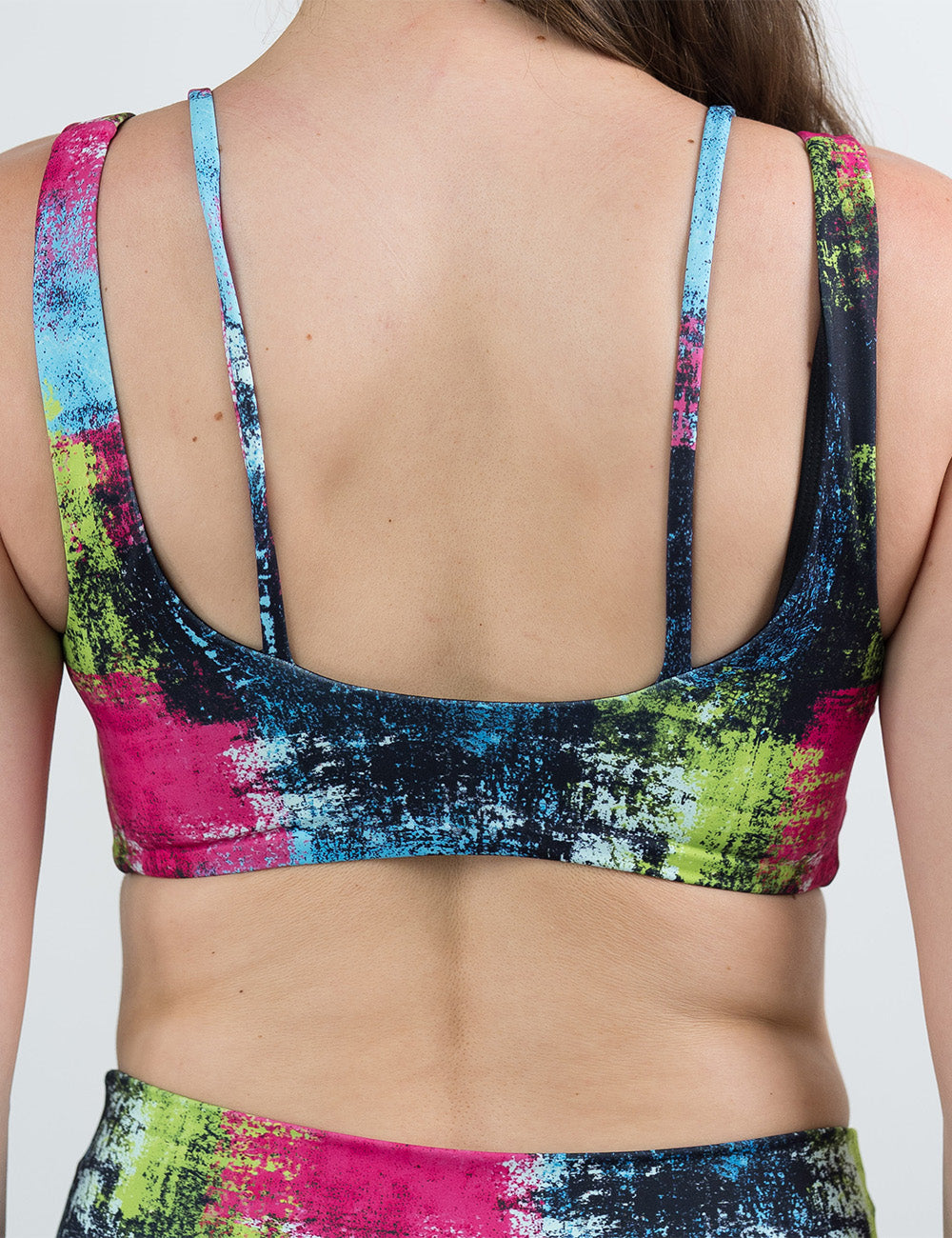 back of the green, pink, and blue grunge pattern bra against a white background