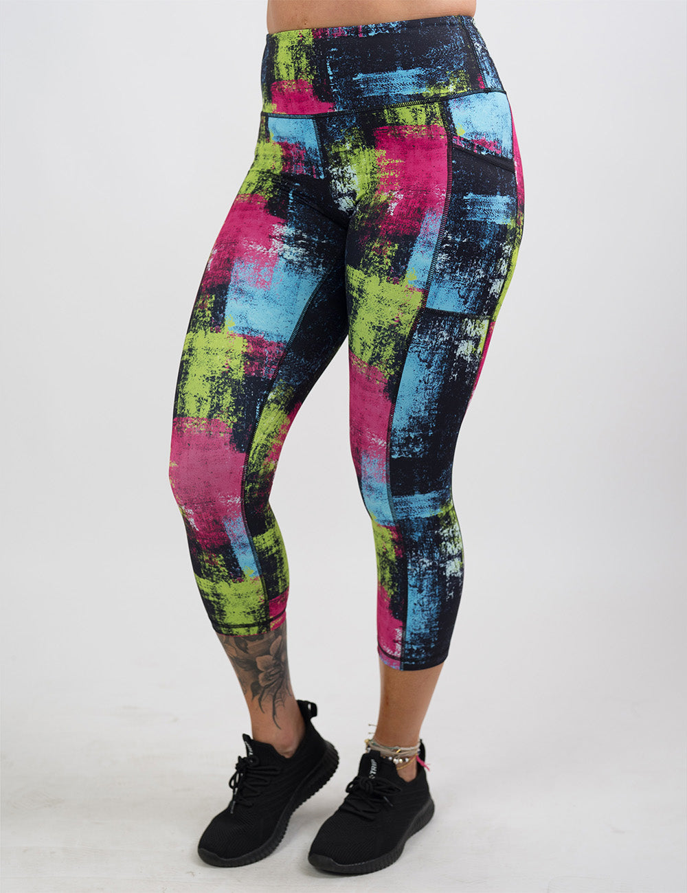 front of the green, pink, and blue grunge pattern capri leggings against a white background