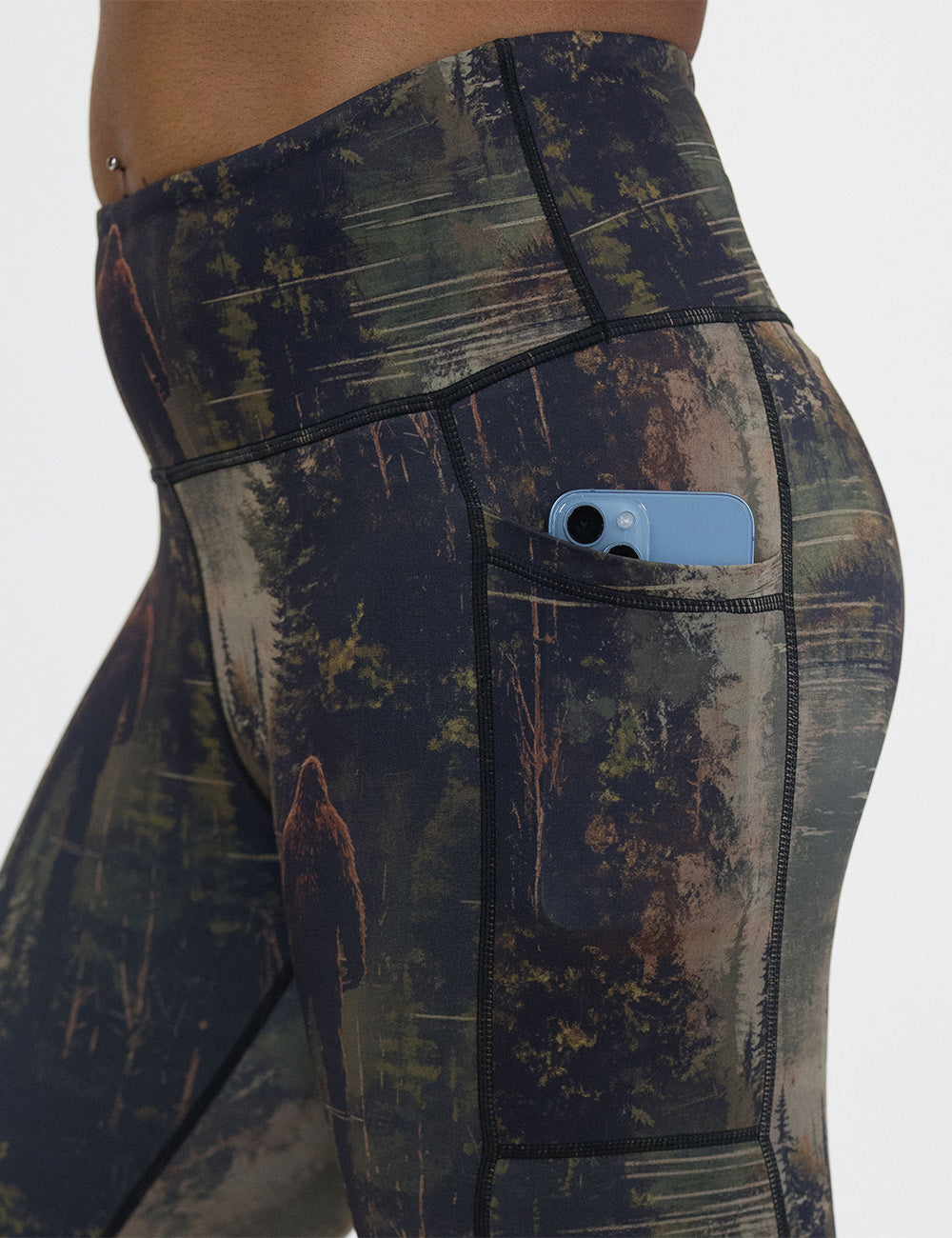close up of the bigfoot in a forest leggings with a phone in its pocket