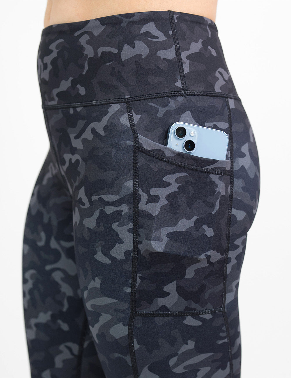 close up of the black camo print leggings with a phone in its pocket against a white background