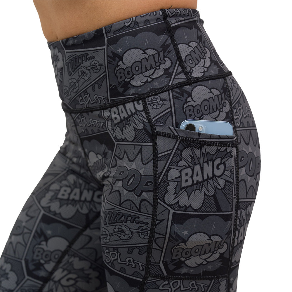 close up of the black and grey comic book print leggings with a phone in the pocket