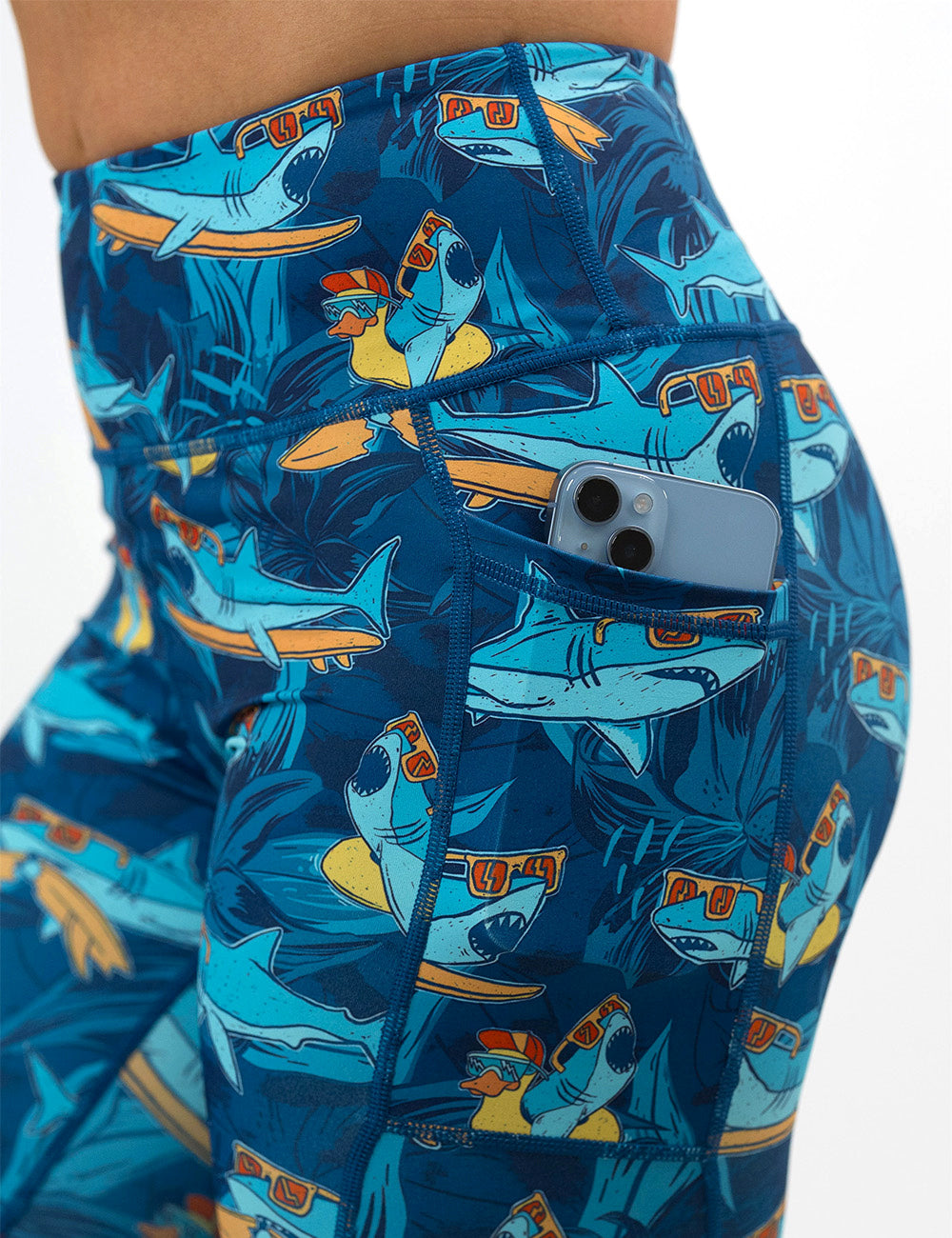 close up of the cartoon sharks surfboarding with sunglasses leggings with a phone in the pocket