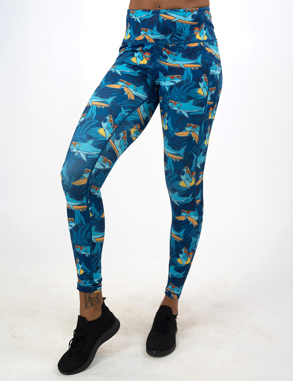 front of the full length cartoon sharks surfboarding with sunglasses leggings against a white background