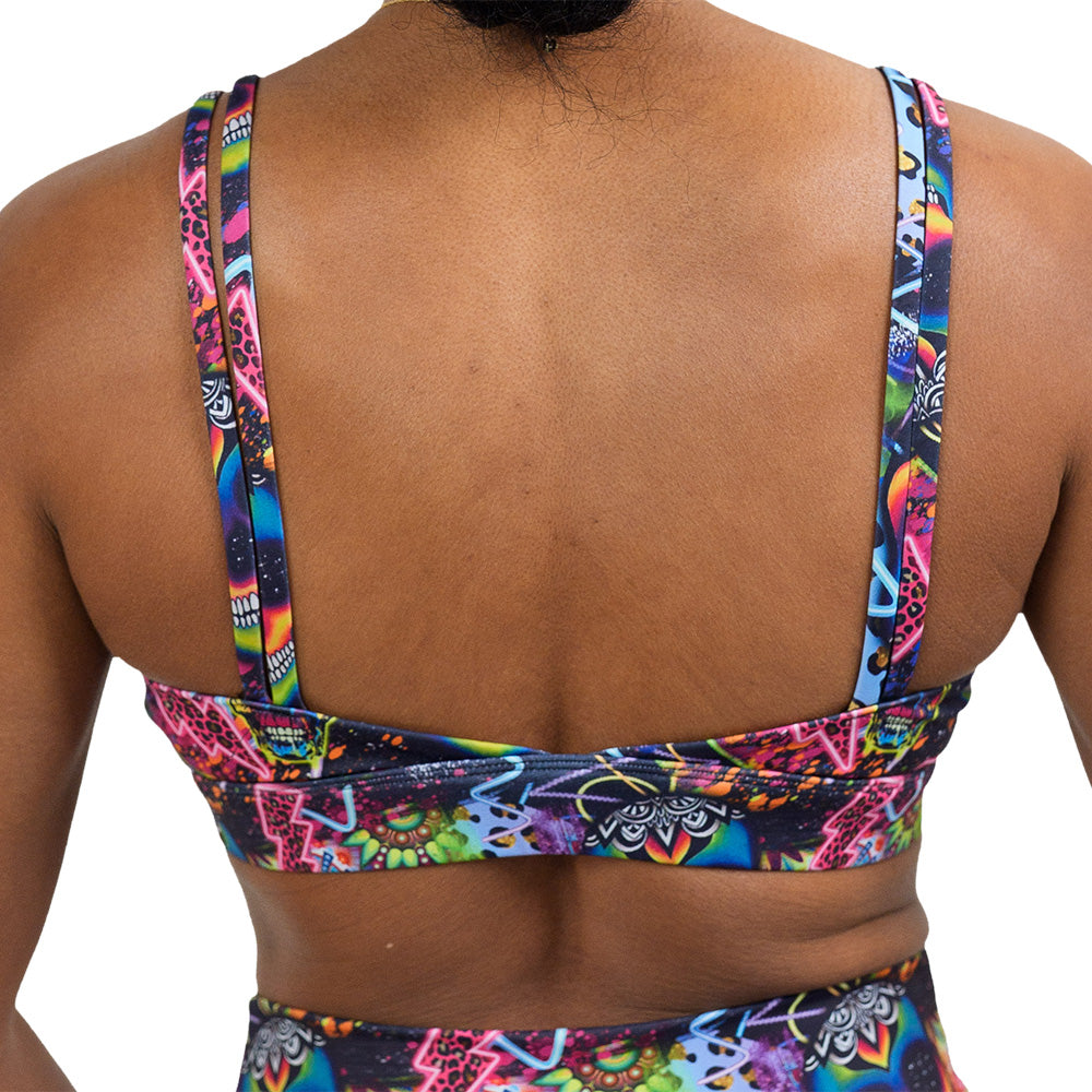back of the the brightly colored psychedelic skulls pattern against a busy background full of designs vista bra against a white background