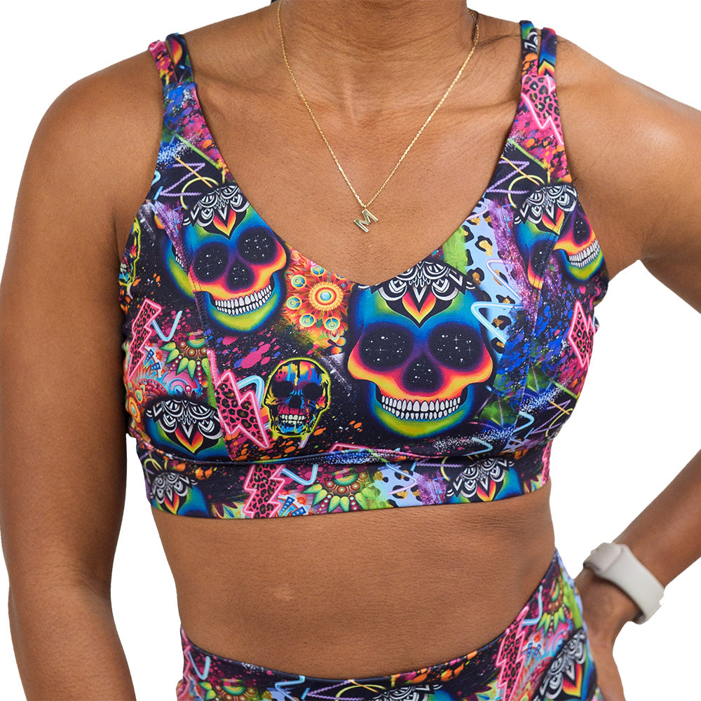 front of the the brightly colored psychedelic skulls pattern against a busy background full of designs vista bra