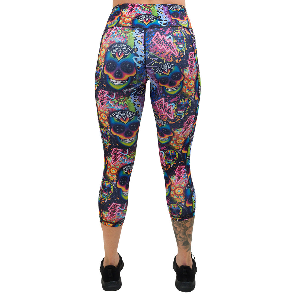 back of the brightly colored psychedelic skulls pattern against a busy background full of designs capri leggings against a white background