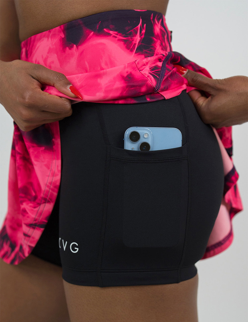 close up of the pink smoke skirt being held up to show the skirts underneath with a phone in its pocket