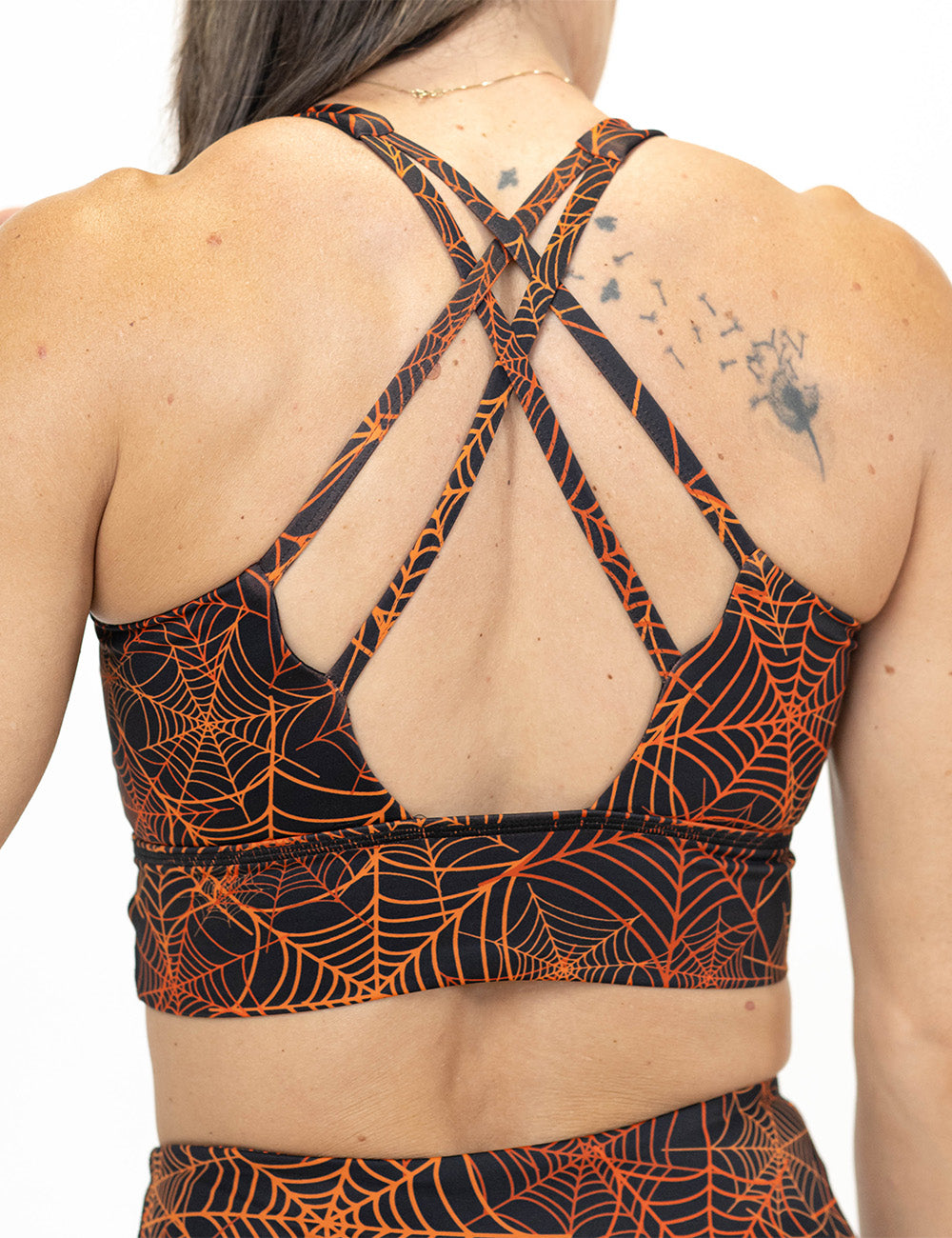 back of the orange spider webs against a black background sports bra against a white background