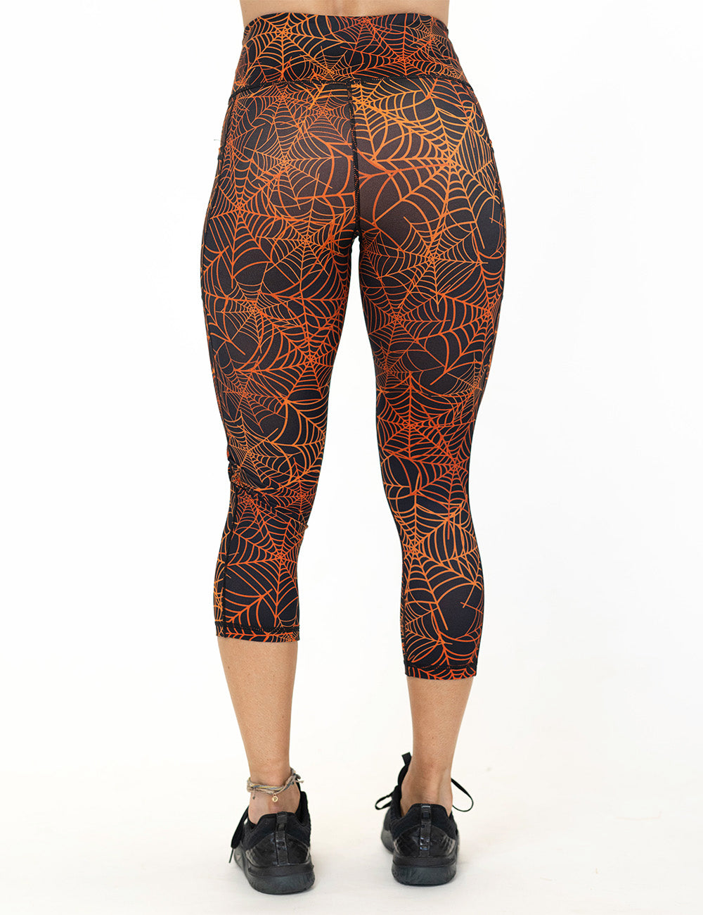 back of the orange spider webs against a black background capri leggings against a white background
