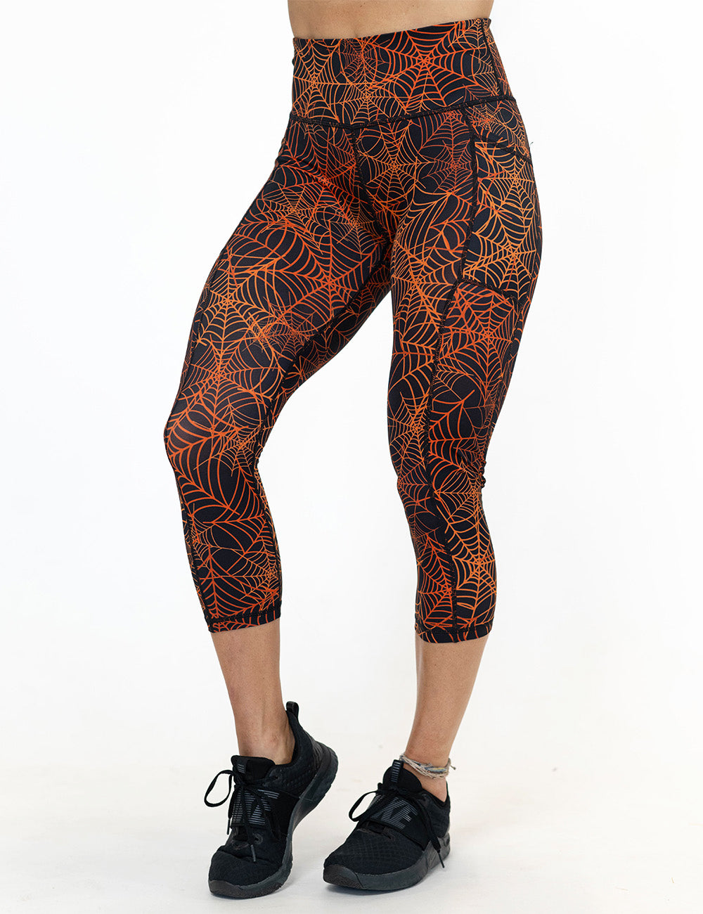 front of the orange spider webs against a black background capri leggings against a white background