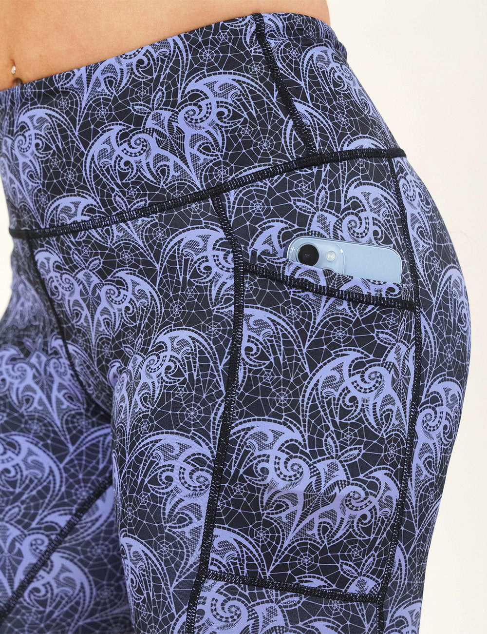 close up of the purple lace bats leggings with a phone in its pocket
