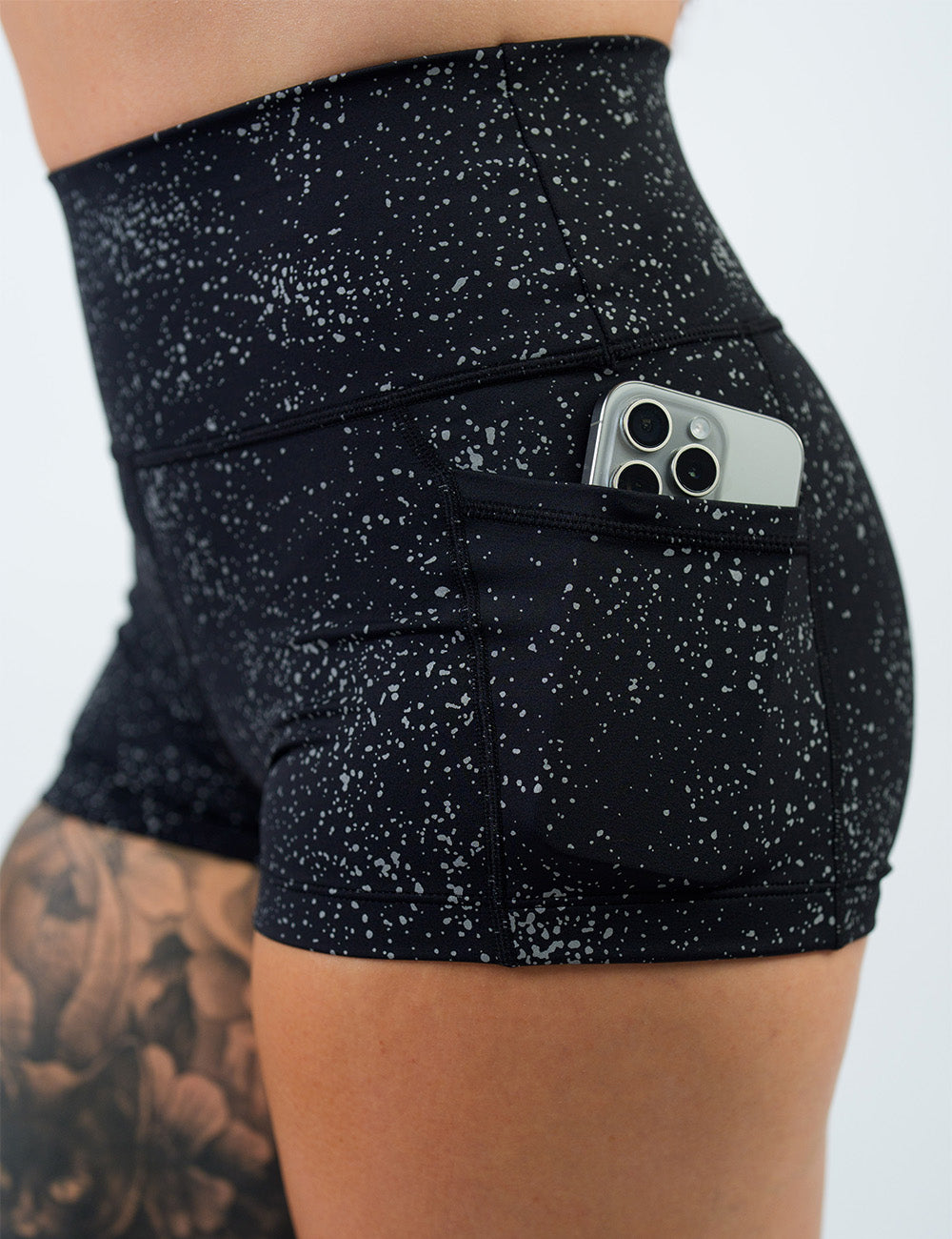 close up of the 2.5 inch black shorts with reflective spots with a phone in its pocket