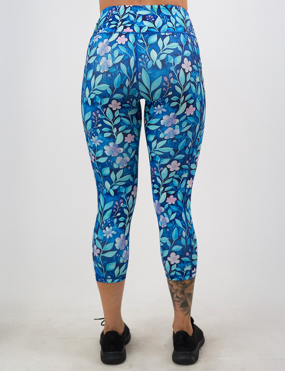 back of the blue flowers and vines capri leggings against a white background