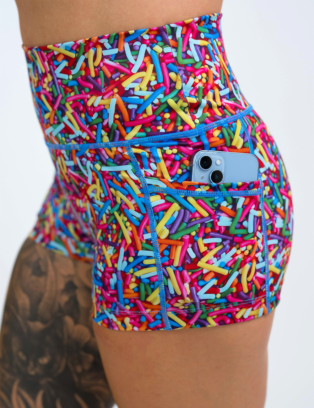 close up of the 2.5 inch rainbow sprinkles shorts with a phone in its pocket against a white background