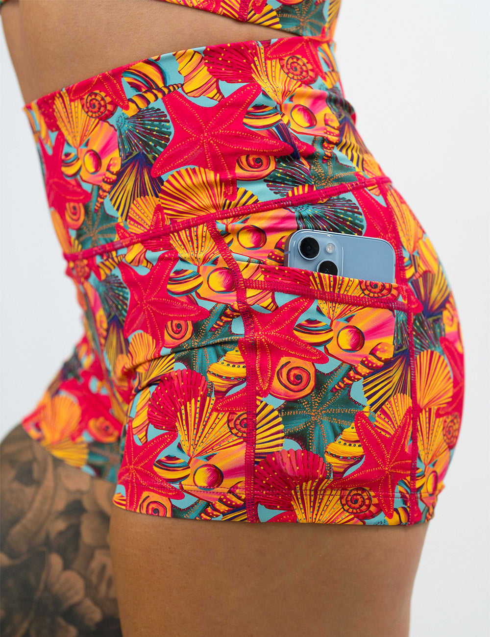 close up of the front of the red starfish with a yellow and blue shell background 2.5 inch shorts with a phone in the pocket