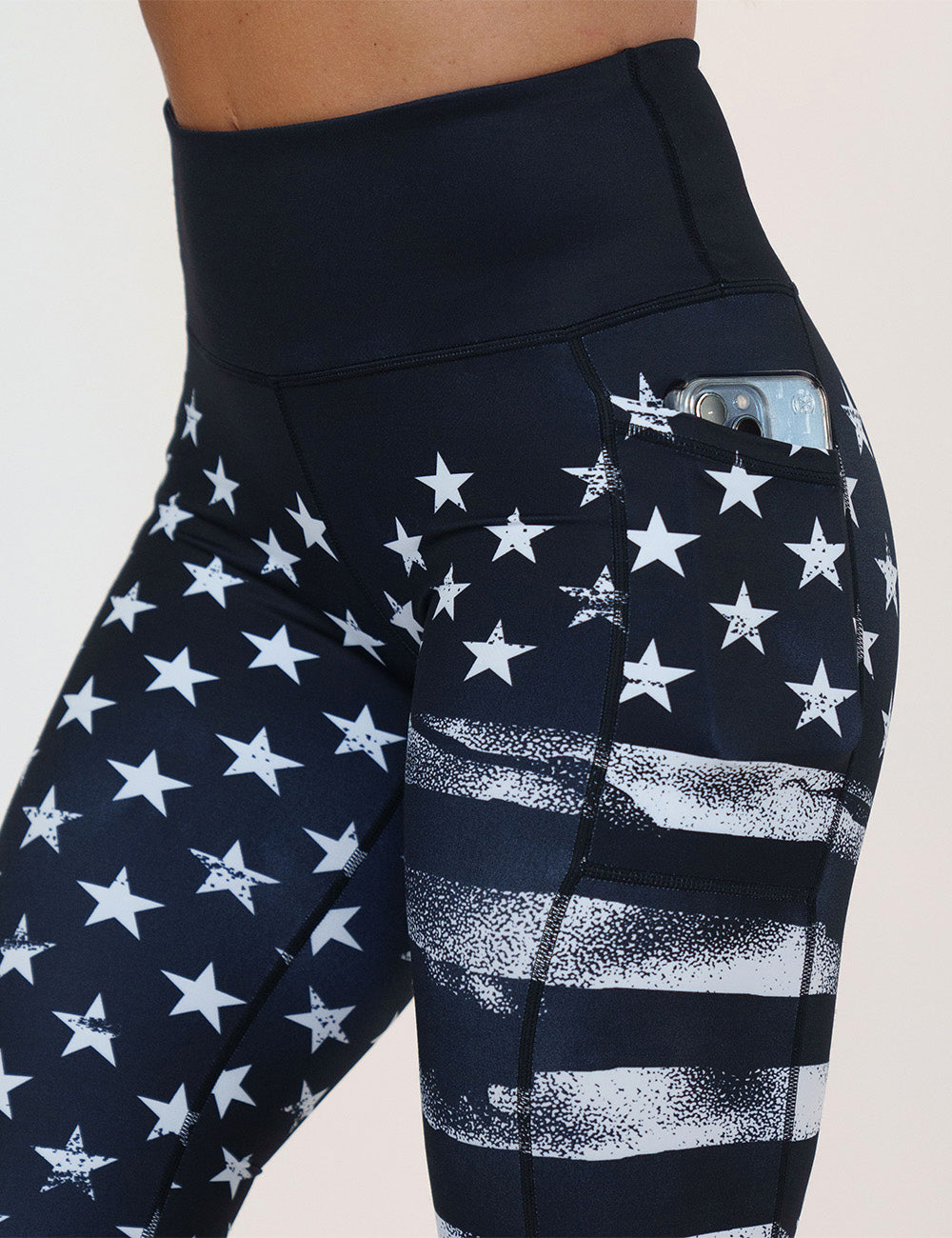 close up of the black leggings with white American flag design on it leggings with a phone in its pocket