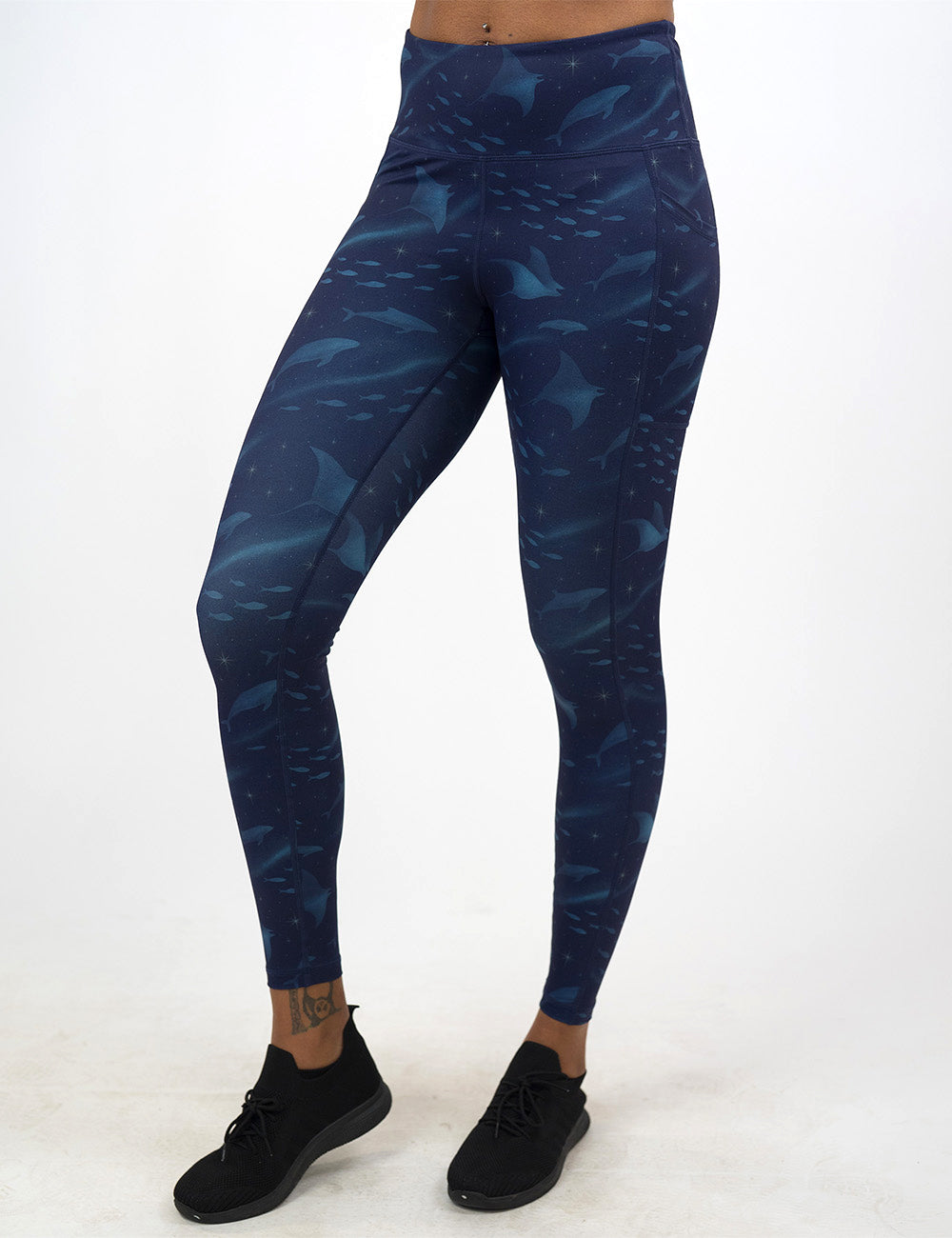 front of the dark blue ocean filled with sting rays, whales, and fish full length leggings against a white background