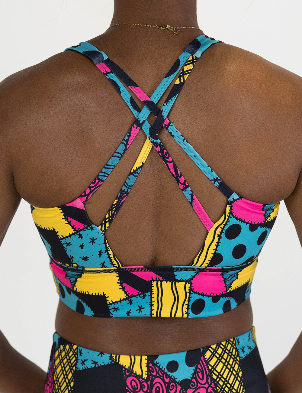 back of the yellow, teal, and pink patchwork designs bra against a white background