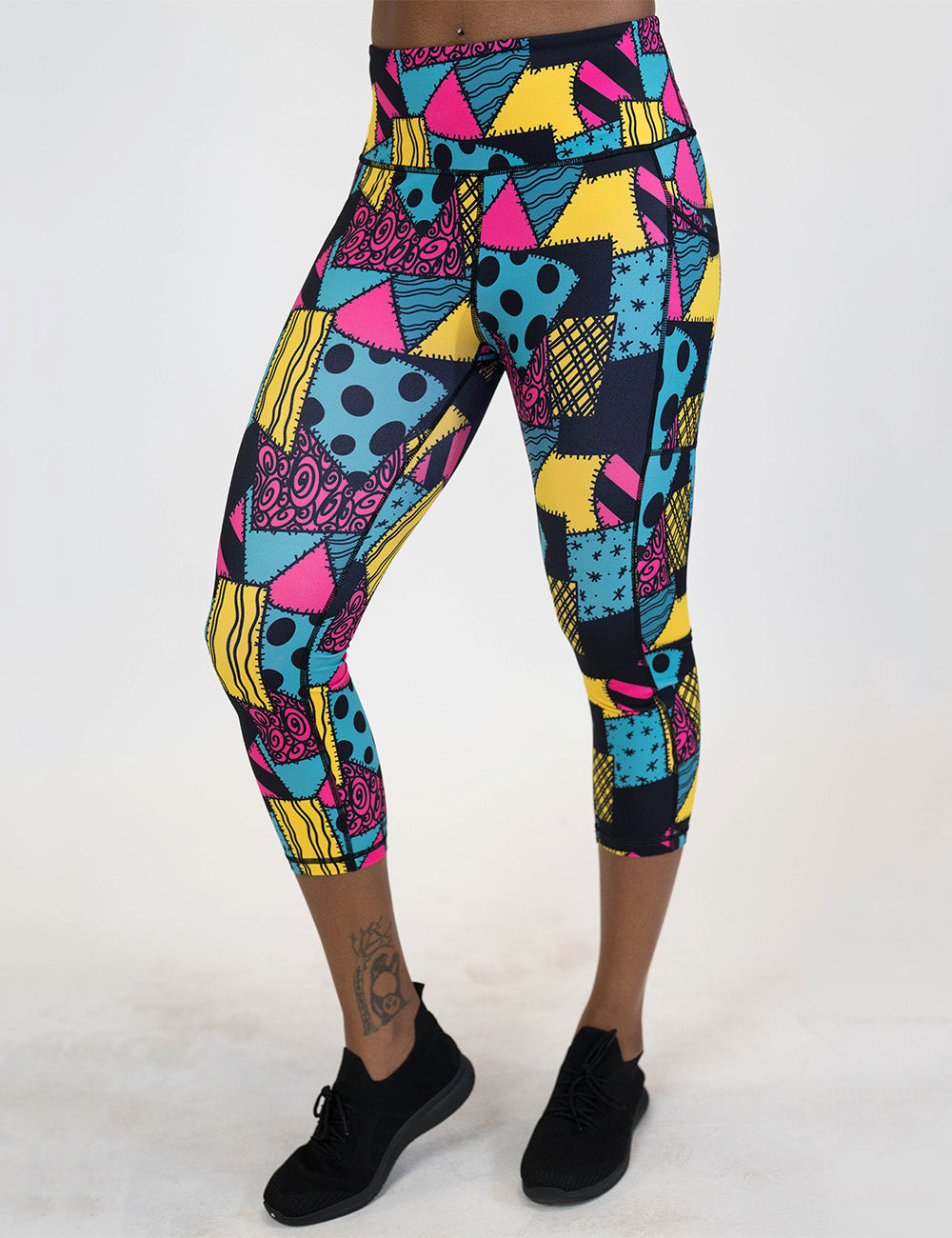 front of the yellow, teal, and pink patchwork design capri leggings against a white background