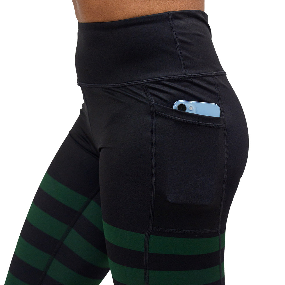 close up of the green stripe against a dark background leggings pocket with a phone in it against a white background