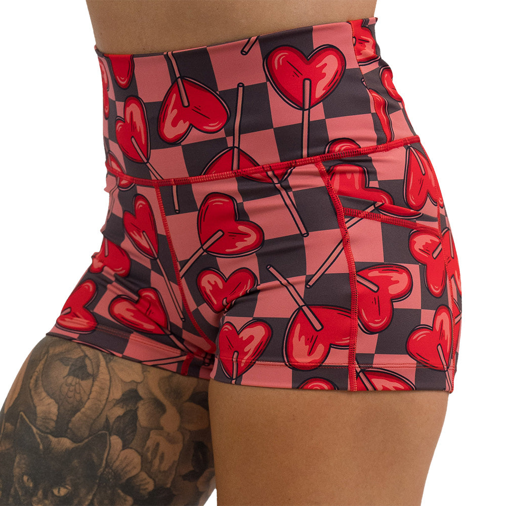 close up of the 2.5 inch heart lollypops on a checker board pattern shorts against a white background
