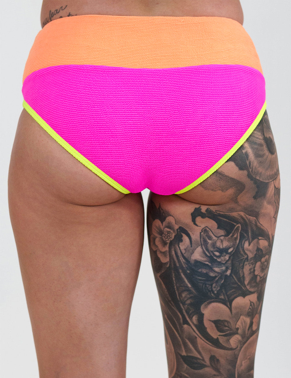 back of the model wearing the pink, orange and yellow bathing suit bottoms against a white background