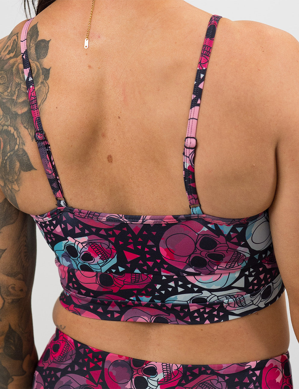 back of the vibrant pink and blue skull swimsuit top against a white background
