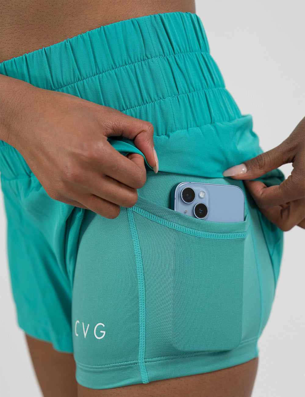 close up of the teal day dream shorts pulled up to show the pocket in the shorts lining holding a phone