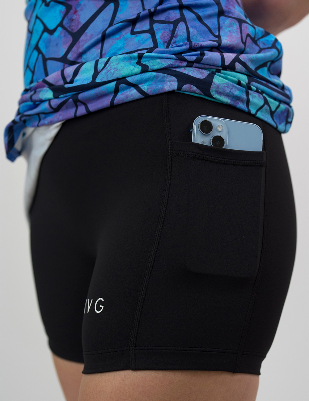 close up of the blue fractured shapes pattern active dress rolled up to show a phone in the pocket against a white background
