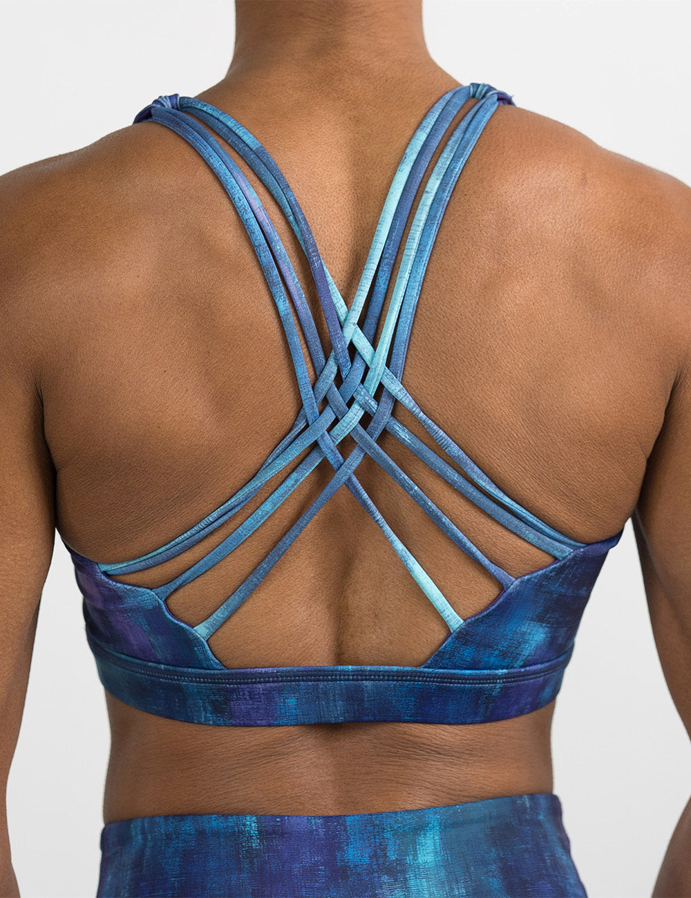 back of the blue, teal, and purple grunge concrete pattern bra against a white background