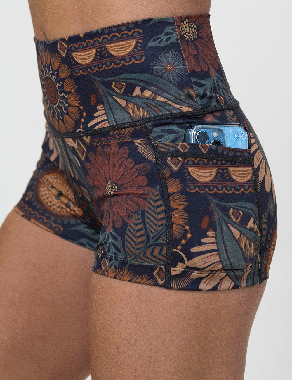 close up of the 2.5 inch paisley flowers shorts with a phone in its pocket