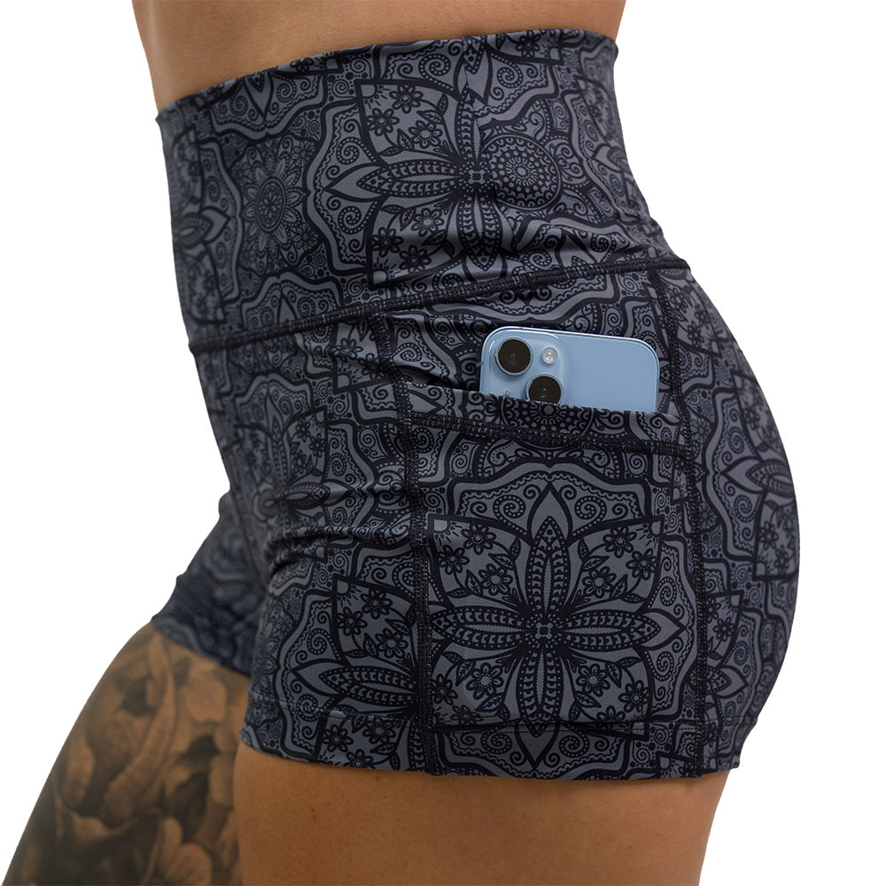 close up of black mandala pattern 2.5 inch shorts with a phone in the pocket against a white background