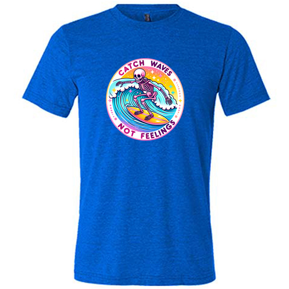 Blue colored shirt with a skeleton surfing graphic on it that says "Catch Waves Not Feelings"
