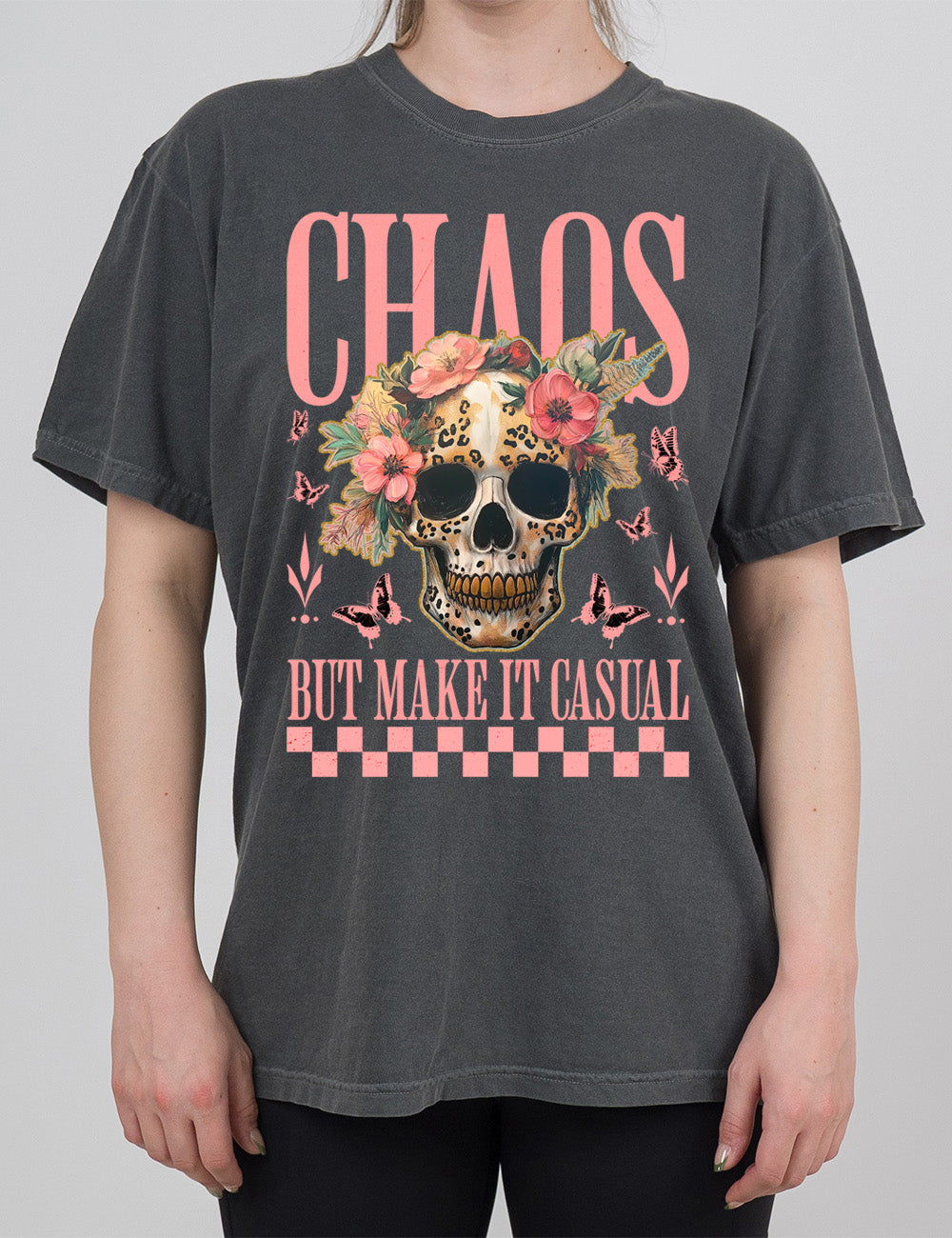 pepper modern tee with the print placement on the front, with the large word "chaos" on it, with the smaller words "but make it casual," and the graphic in between this of a gold-toothed skull with some leopard print, with a crown of flowers, surrounded by butterflies