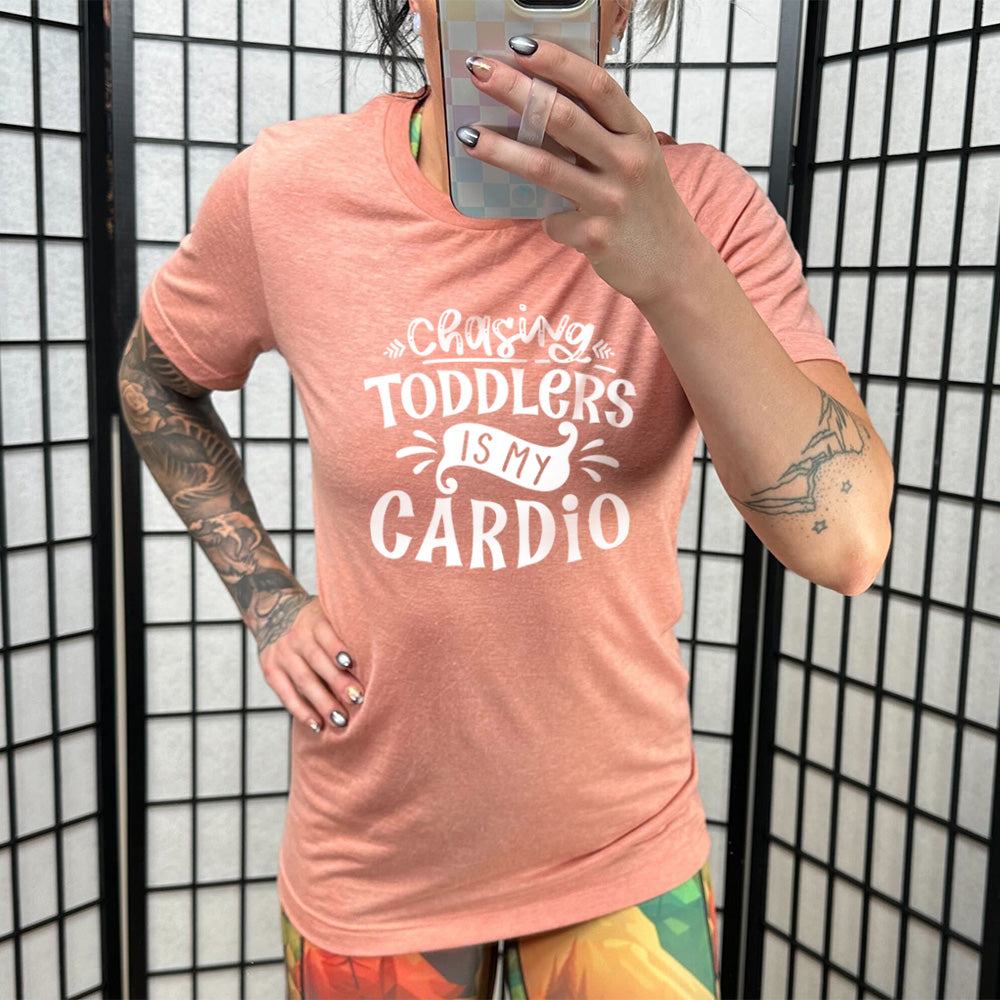 Sunset colored shirt with a graphic on it that says "Chasing Toddlers is My Cardio"