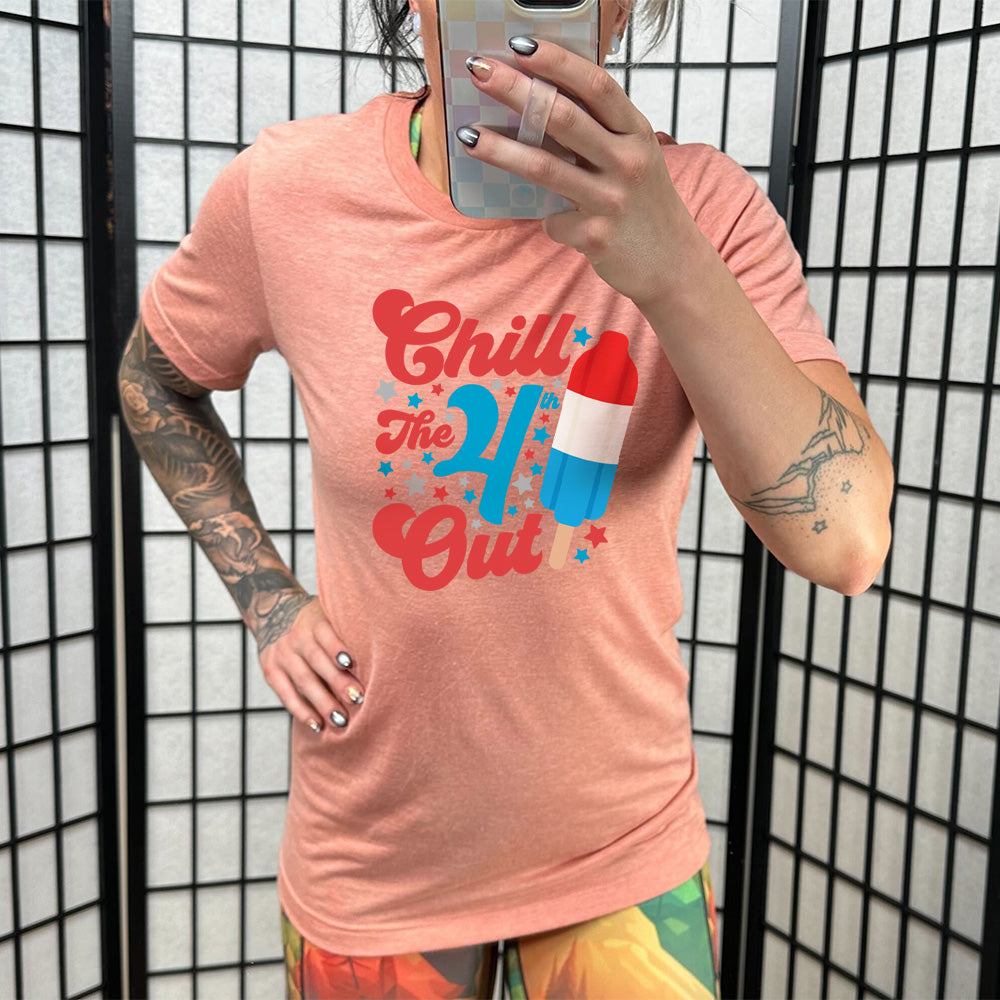 Model wearing sunset colored shirt with a red white and blue popsicle graphic on it that says "Chill The 4th Out"