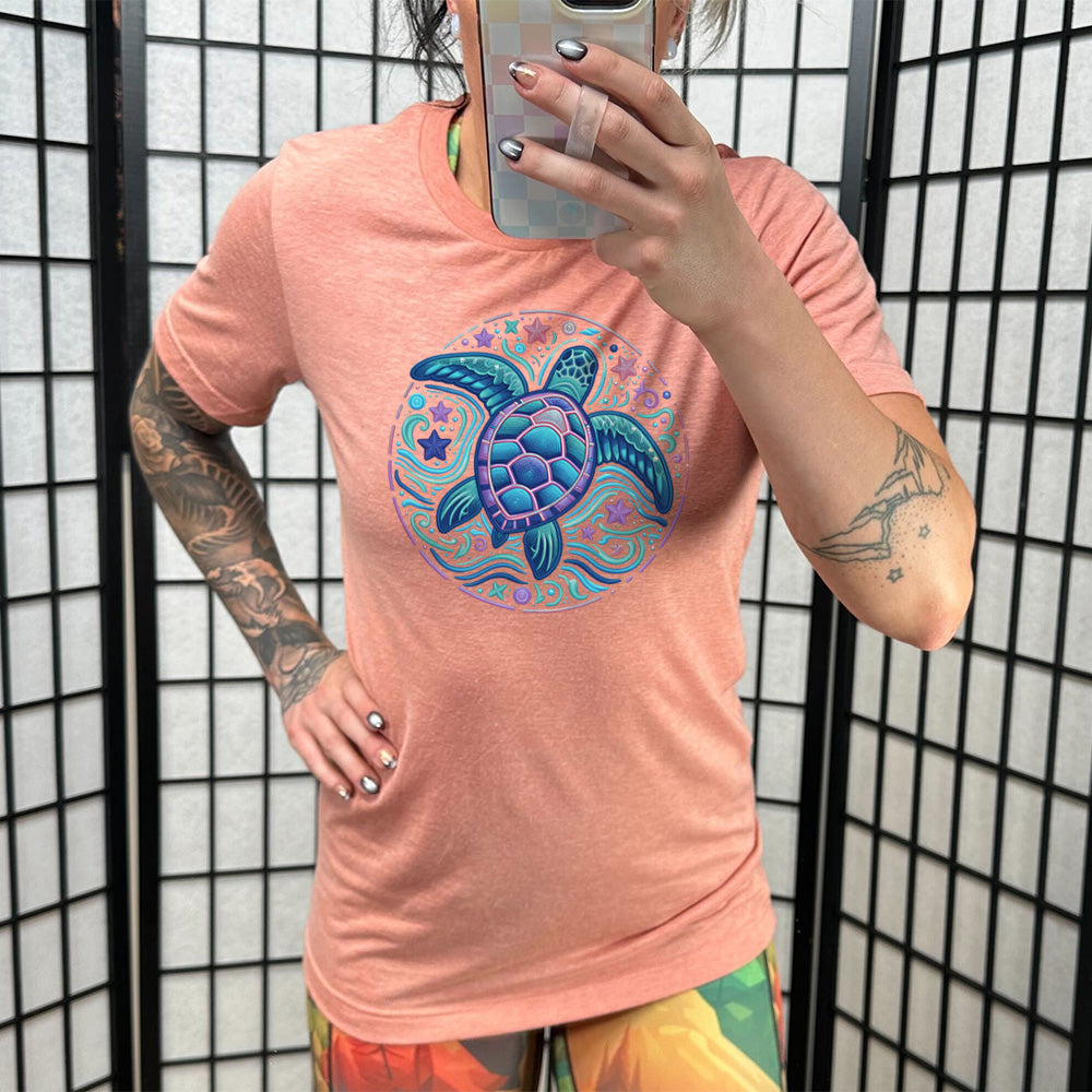 Model wearing sunset colored shirt with a colorful turtle graphic on it