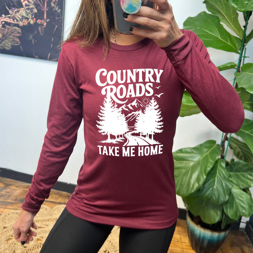 heather cardinal long sleeve with the words "country roads take me home" on it, and the graphic of a road going through tall trees, with mountains beyond, and the sun