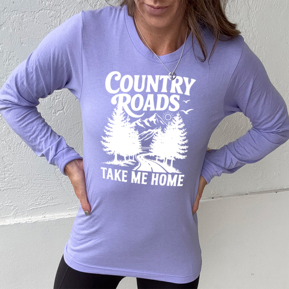 heather dark lavender long sleeve with the words "country roads take me home" on it, and the graphic of a road going through tall trees, with mountains beyond, and the sun