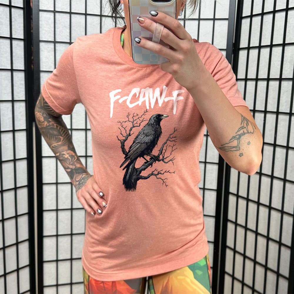 Model wearing sunset colored shirt with crow on branch graphic on it that says "F-CAW-F"