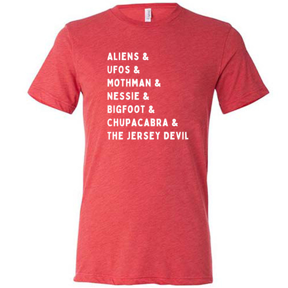 Red colored shirt with graphic on it that says "ALIENS & UFOS & MOTHMAN & NESSIE & BIGFOOT & CHUPACABRA & THE JERSEY DEVIL"